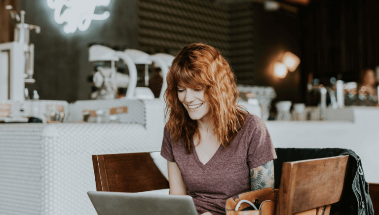 Une dame souriante, derrière un PC.